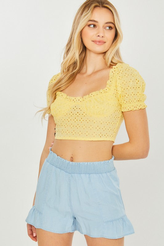 A close-up of a person wearing light blue, high-waisted Woven Solid Shorts with an elastic waistband and ruffled hem, highlighting the breathable fabric for comfortable casual wear.