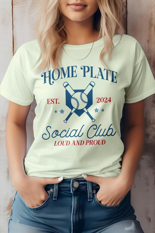 Person wearing a white "Home Plate, Social Club, Baseball Graphic Tee" featuring crossed bats and a baseball graphic, along with "EST. 2024" and "LOUD AND PROUD" text, paired with blue jeans.