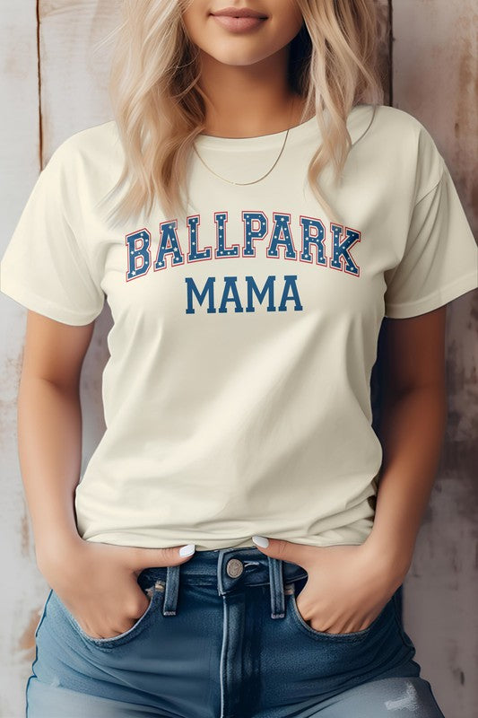 A person wearing a light gray Ballpark MAMA Baseball Graphic Tee has blonde hair and is standing with their hands in the pockets of blue denim jeans, effortlessly showcasing casual sports apparel.