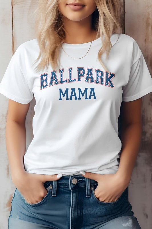 A person wearing a light gray Ballpark MAMA Baseball Graphic Tee has blonde hair and is standing with their hands in the pockets of blue denim jeans, effortlessly showcasing casual sports apparel.