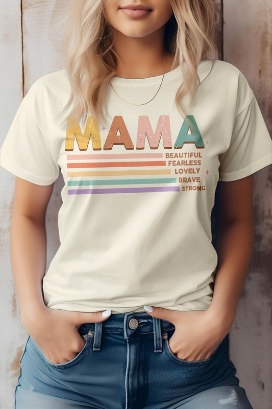 A person wearing the MAMA Graphic Tee, a beige shirt featuring the word "MAMA" in colorful letters and descriptions like "Beautiful," "Fearless," "Lovely," "Brave," and "Strong" written below—perfect for Mother's Day.