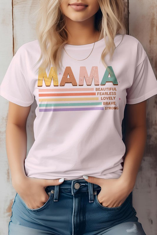 A person wearing the MAMA Graphic Tee, a beige shirt featuring the word "MAMA" in colorful letters and descriptions like "Beautiful," "Fearless," "Lovely," "Brave," and "Strong" written below—perfect for Mother's Day.