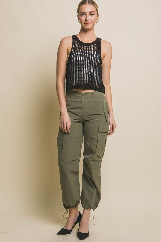 A person poses in a beige Sleeveless Open Knit Crop Top paired with tan drawstring pants against a light background.