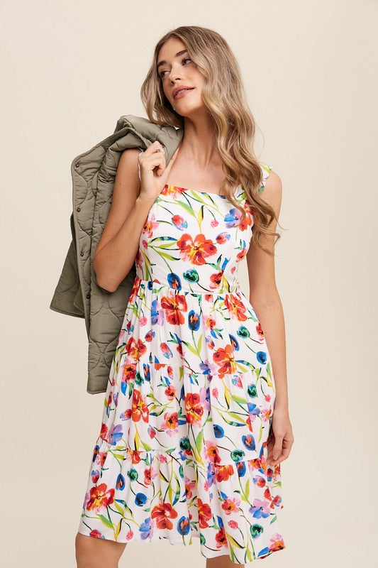 A woman can be seen twirling in the Flower Print Square Neck Dress, which features ruffle shoulder straps, while maintaining a neutral expression against a plain background.