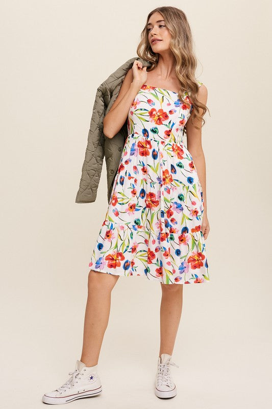 A woman can be seen twirling in the Flower Print Square Neck Dress, which features ruffle shoulder straps, while maintaining a neutral expression against a plain background.