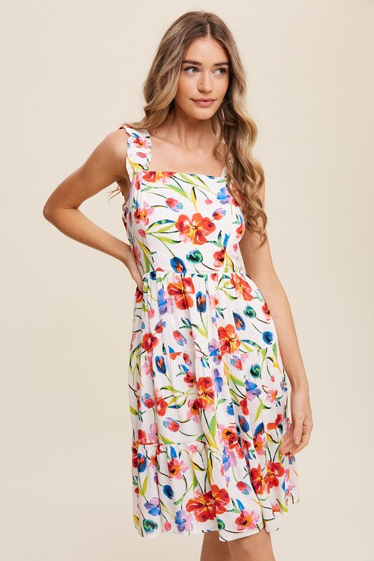 A woman can be seen twirling in the Flower Print Square Neck Dress, which features ruffle shoulder straps, while maintaining a neutral expression against a plain background.