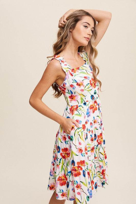 A woman can be seen twirling in the Flower Print Square Neck Dress, which features ruffle shoulder straps, while maintaining a neutral expression against a plain background.