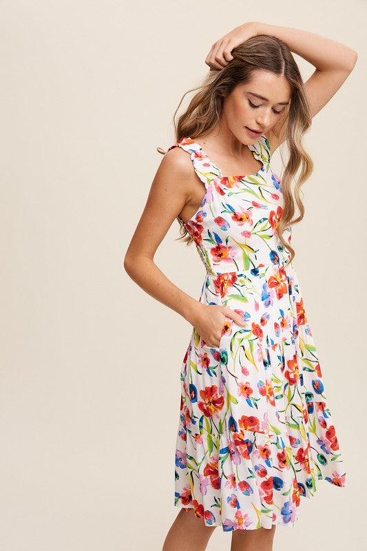 A woman can be seen twirling in the Flower Print Square Neck Dress, which features ruffle shoulder straps, while maintaining a neutral expression against a plain background.