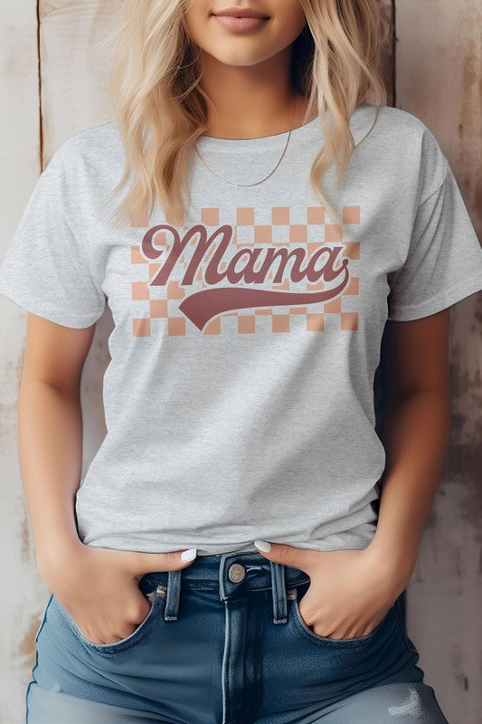 A person wearing a light-colored "Mama Retro Checkered Graphic Tee" with the words "Mama Retro" printed in a retro font stands against a wooden background, embodying the perfect vibe for Mother's Day.