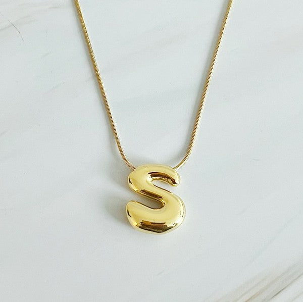 Gold necklaces featuring distinctive, balloon-shaped pendants of the letters E, N, K, L, M, and T against a white backdrop. These Balloon Letter Initial Necklaces are trend-setting and crafted in 18k gold plating for a stylish complement to any ensemble.