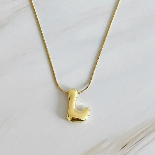 Gold necklaces featuring distinctive, balloon-shaped pendants of the letters E, N, K, L, M, and T against a white backdrop. These Balloon Letter Initial Necklaces are trend-setting and crafted in 18k gold plating for a stylish complement to any ensemble.