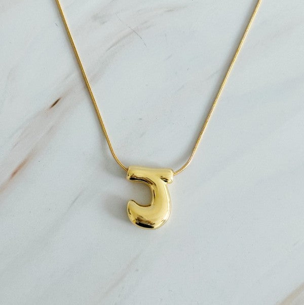 Gold necklaces featuring distinctive, balloon-shaped pendants of the letters E, N, K, L, M, and T against a white backdrop. These Balloon Letter Initial Necklaces are trend-setting and crafted in 18k gold plating for a stylish complement to any ensemble.