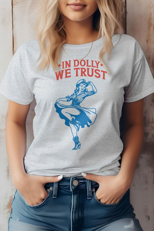 A person wearing the "In Dolly We Trust, Retro Western Graphic Tee" made from eco-friendly materials, showcasing a dancing woman graphic with the text "IN DOLLY WE TRUST" in red on a white T-shirt.