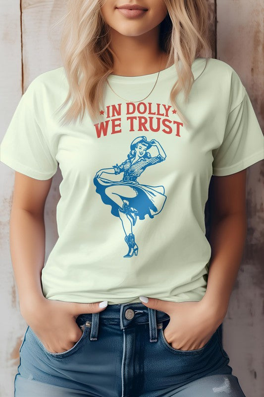 A person wearing the "In Dolly We Trust, Retro Western Graphic Tee" made from eco-friendly materials, showcasing a dancing woman graphic with the text "IN DOLLY WE TRUST" in red on a white T-shirt.