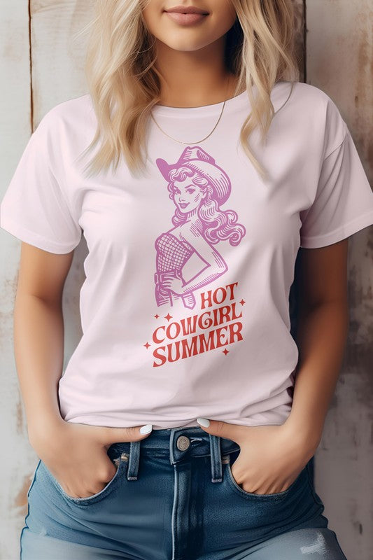 A person wearing the "Hot Cowgirl Summer" Retro Western Graphic Tee, which features an illustrated cowgirl and the text "Hot Cowgirl Summer." They have their hands in the pockets of their denim shorts, highlighting a stylish look made from eco-friendly materials.