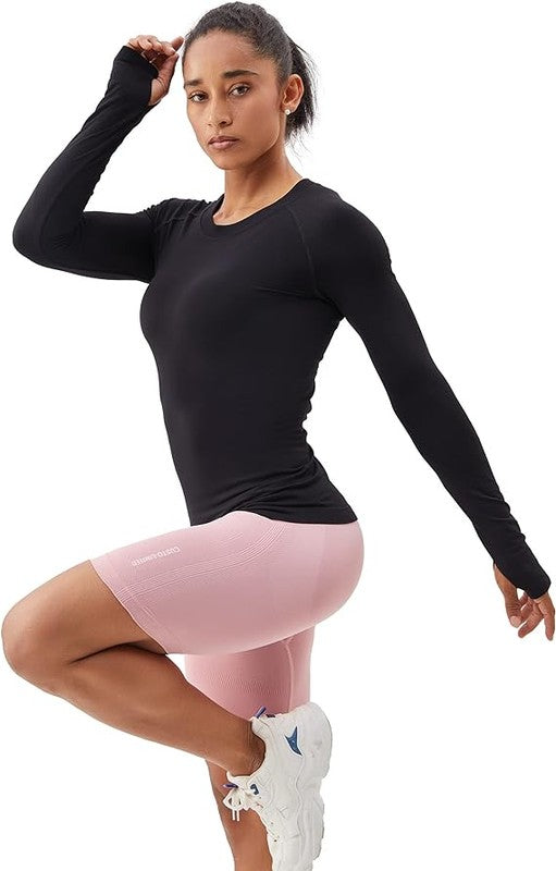 A person is standing in a bright yellow Long Sleeve Workout Shirt for Women, paired with black leggings and white sneakers, posing against a white background. This outfit perfectly showcases stylish athletic wear.