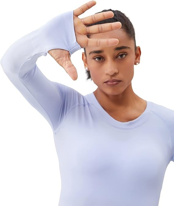 A person is standing in a bright yellow Long Sleeve Workout Shirt for Women, paired with black leggings and white sneakers, posing against a white background. This outfit perfectly showcases stylish athletic wear.