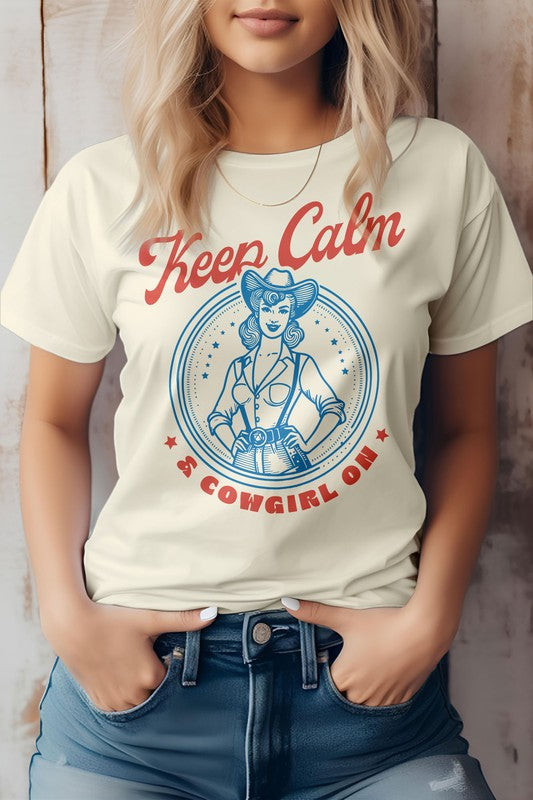 A person wearing the "Keep Calm Cowgirl On Western Graphic Tee," a white t-shirt featuring a retro western design of a cowgirl and the phrase "Keep Calm & Cowgirl On" in red and blue text. The t-shirt is made from eco-friendly materials.