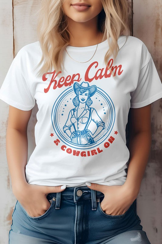 A person wearing the "Keep Calm Cowgirl On Western Graphic Tee," a white t-shirt featuring a retro western design of a cowgirl and the phrase "Keep Calm & Cowgirl On" in red and blue text. The t-shirt is made from eco-friendly materials.