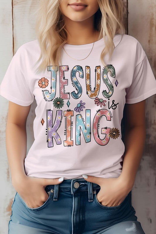 A person wearing the "Jesus is King, Christian Graphic Tee," a white t-shirt adorned with vibrant text and floral designs, crafted from superior combed cotton.