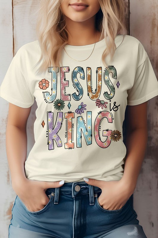 A person wearing the "Jesus is King, Christian Graphic Tee," a white t-shirt adorned with vibrant text and floral designs, crafted from superior combed cotton.