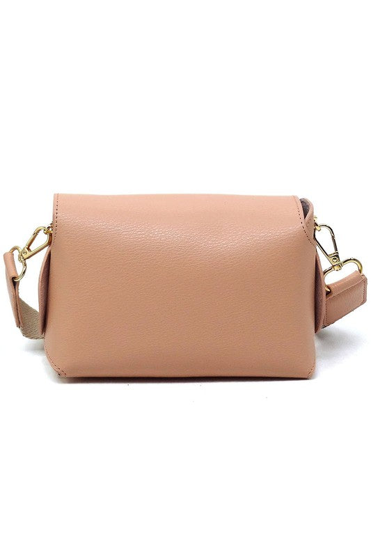 The Bamboo Twist Lock Flap Crossbody Bag is a small peach-colored bag made from faux vegan leather. It features a chic bamboo twist lock for added elegance, a gold clasp, and an adjustable patterned shoulder strap with black and brown geometric designs.