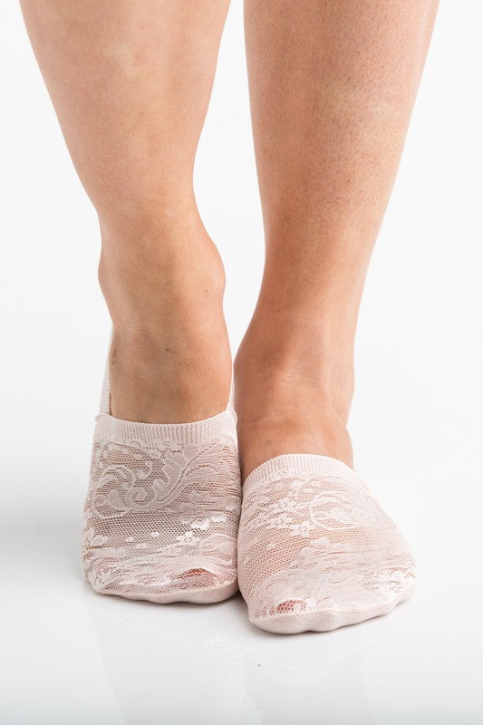 Wearing a pair from the No Slip Floral Lace Sneaker Socks- 3 Pack, her feet are stylishly clad in nude-colored no-show socks featuring a delicate floral lace pattern. A small ankle tattoo with three dots adds a personal touch, while the no-slip design ensures they stay perfectly in place.