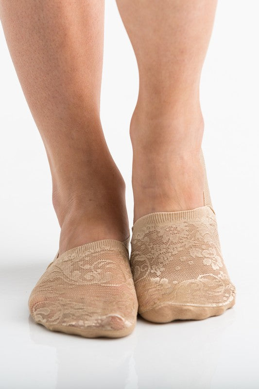 Wearing a pair from the No Slip Floral Lace Sneaker Socks- 3 Pack, her feet are stylishly clad in nude-colored no-show socks featuring a delicate floral lace pattern. A small ankle tattoo with three dots adds a personal touch, while the no-slip design ensures they stay perfectly in place.