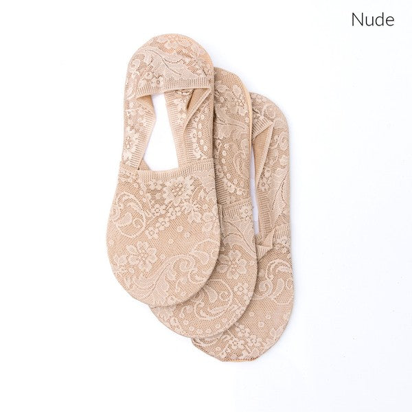 Wearing a pair from the No Slip Floral Lace Sneaker Socks- 3 Pack, her feet are stylishly clad in nude-colored no-show socks featuring a delicate floral lace pattern. A small ankle tattoo with three dots adds a personal touch, while the no-slip design ensures they stay perfectly in place.