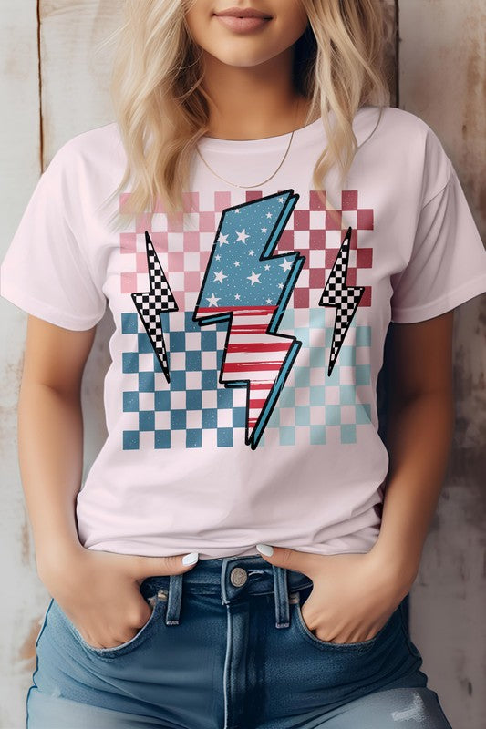 Person wearing the America Flag Lightning Bolt Checker Graphic Tee, a white t-shirt with a lightning bolt overlaying a red, white, and blue checkered pattern—perfect for celebrating the 4th of July. Hands are in the front pockets of blue jeans.