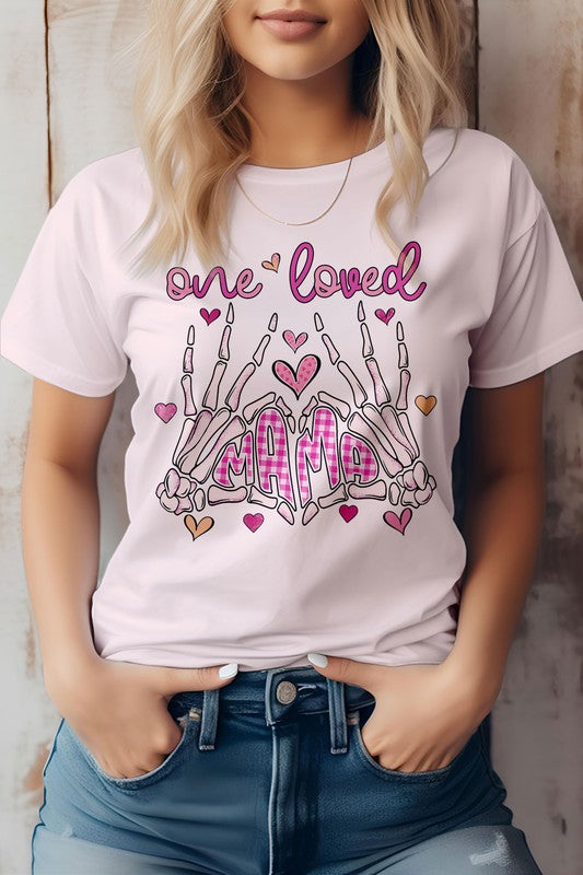 Woman wearing the "One Loved Mama" Mother's Day graphic tee, an eco-friendly pink shirt featuring decorative text and skeleton hand illustrations.