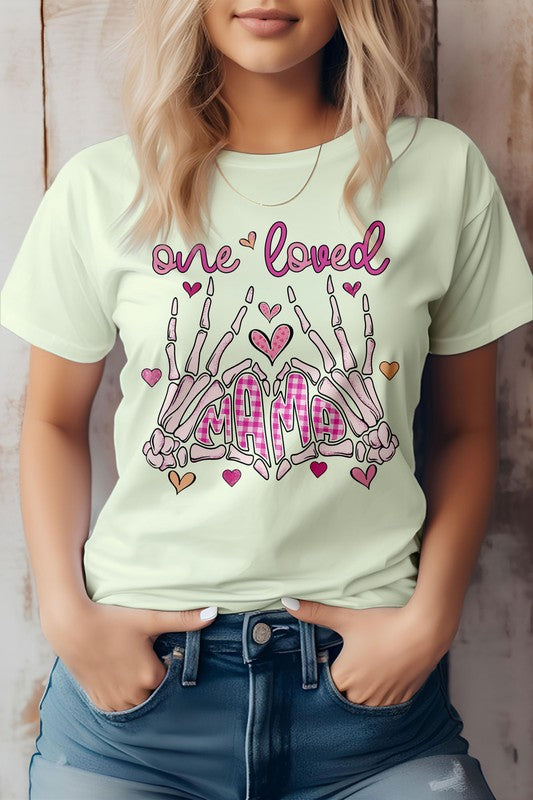 Woman wearing the "One Loved Mama" Mother's Day graphic tee, an eco-friendly pink shirt featuring decorative text and skeleton hand illustrations.