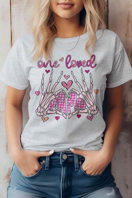 Woman wearing the "One Loved Mama" Mother's Day graphic tee, an eco-friendly pink shirt featuring decorative text and skeleton hand illustrations.