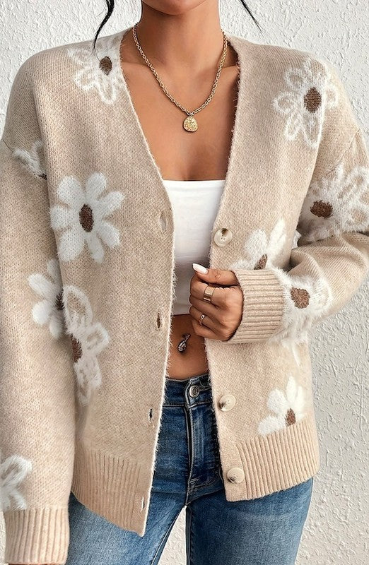 A person wearing a beige Floral Pattern Cardigan with white and brown flower patterns, a white cropped top, blue jeans, and a gold necklace.