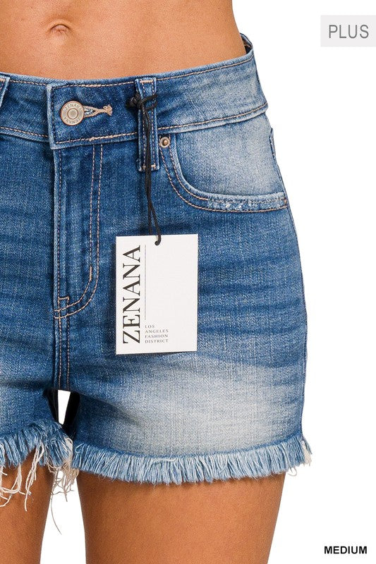 Close-up of a person wearing the Plus Mid Rise Raw Frayed Hem Denim Shorts, crafted from stretch denim.