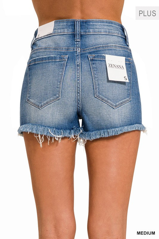 Close-up of a person wearing the Plus Mid Rise Raw Frayed Hem Denim Shorts, crafted from stretch denim.