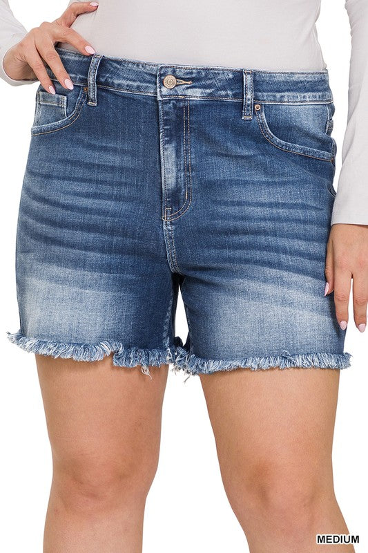 A person is wearing Zenana's Plus Mid Rise Raw Frayed Hem Denim Shorts in blue.