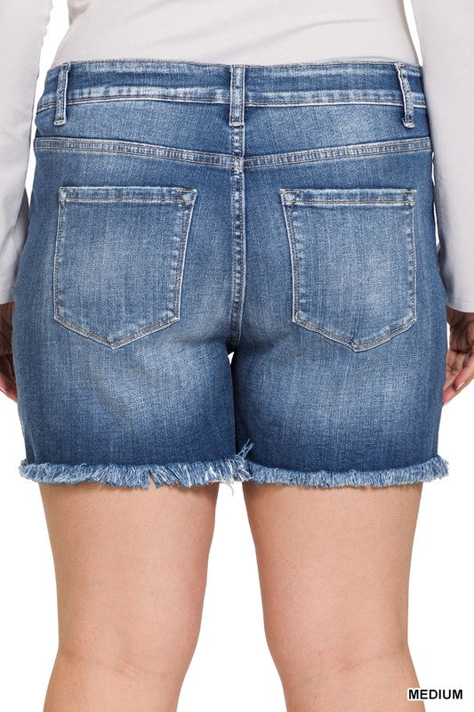 A person is wearing Zenana's Plus Mid Rise Raw Frayed Hem Denim Shorts in blue.