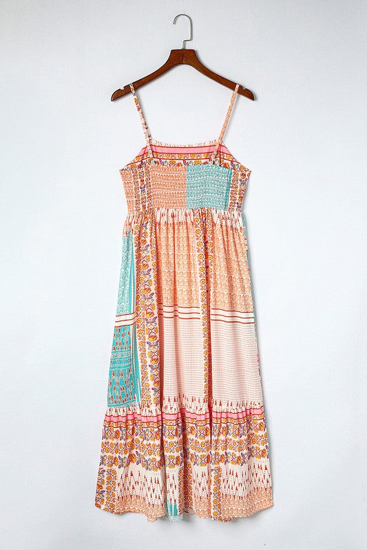 A Patchwork mint coral long sundress, featuring a Bohemian-inspired colorful patchwork print, sleeveless design with spaghetti straps and a square neckline, along with an A-line silhouette, is hanging on a wooden hanger against a plain white background.
