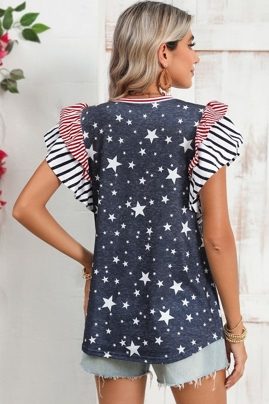 A woman displays American pride in the Flag Stripe Ruffle Sleeve Star Shirt USA, featuring a star pattern and striped ruffled sleeves, paired with denim shorts. Her look is accentuated with bracelets and a necklace, all crafted from soft cotton fabric for added comfort and style.