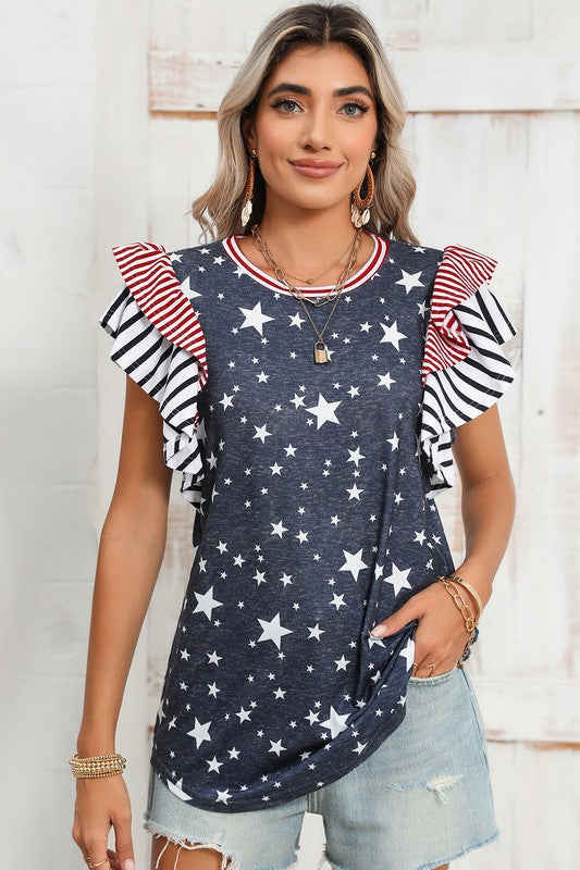 A woman displays American pride in the Flag Stripe Ruffle Sleeve Star Shirt USA, featuring a star pattern and striped ruffled sleeves, paired with denim shorts. Her look is accentuated with bracelets and a necklace, all crafted from soft cotton fabric for added comfort and style.