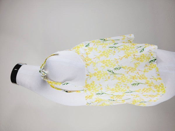 Yellow cotton tank top with a floral design and adjustable spaghetti straps, styled against a leafy green plant on a white background.