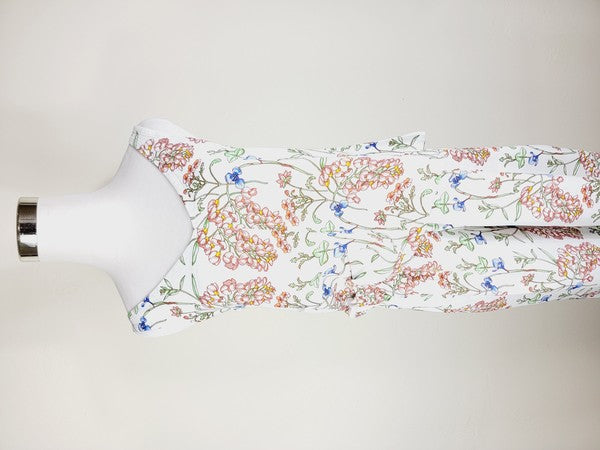 White pants with a vibrant floral pattern showcasing shades of blue, green, red, and pink. Made from airy cotton fabric, these wide-leg pants come with an elastic waistband for ultimate comfort.