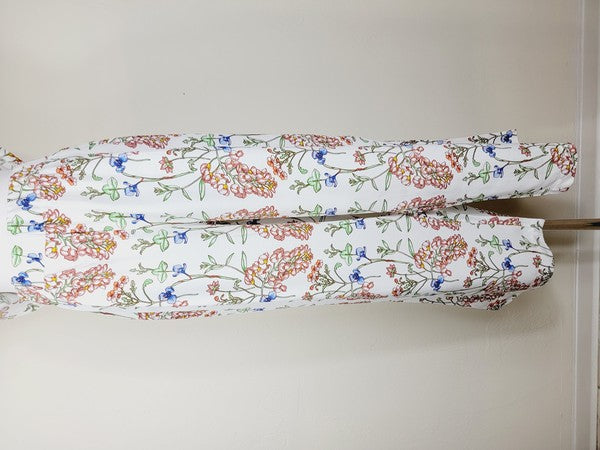 White pants with a vibrant floral pattern showcasing shades of blue, green, red, and pink. Made from airy cotton fabric, these wide-leg pants come with an elastic waistband for ultimate comfort.