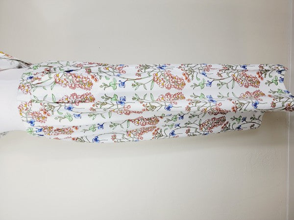 White pants with a vibrant floral pattern showcasing shades of blue, green, red, and pink. Made from airy cotton fabric, these wide-leg pants come with an elastic waistband for ultimate comfort.