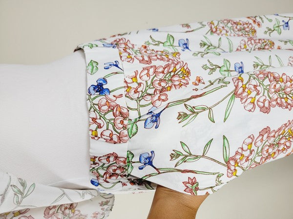 White pants with a vibrant floral pattern showcasing shades of blue, green, red, and pink. Made from airy cotton fabric, these wide-leg pants come with an elastic waistband for ultimate comfort.