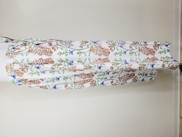 White pants with a vibrant floral pattern showcasing shades of blue, green, red, and pink. Made from airy cotton fabric, these wide-leg pants come with an elastic waistband for ultimate comfort.