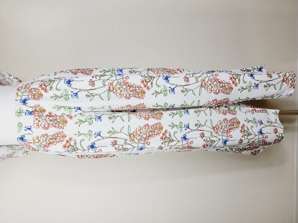 White pants with a vibrant floral pattern showcasing shades of blue, green, red, and pink. Made from airy cotton fabric, these wide-leg pants come with an elastic waistband for ultimate comfort.