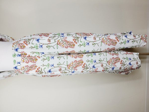 White pants with a vibrant floral pattern showcasing shades of blue, green, red, and pink. Made from airy cotton fabric, these wide-leg pants come with an elastic waistband for ultimate comfort.