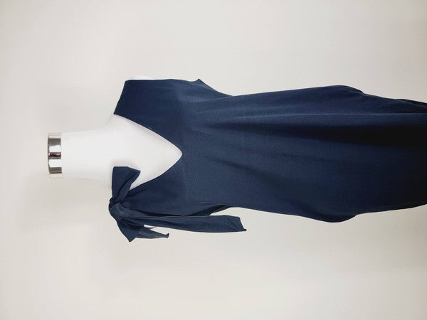 A mannequin displays a Cotton Jersey dress in navy blue with side pockets, featuring a sleeveless design and a large bow on the left shoulder.